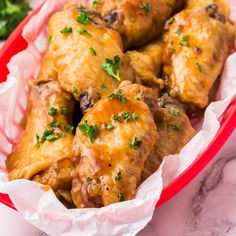 chicken wings with parsley in a red basket on a marble countertop, ready to be eaten