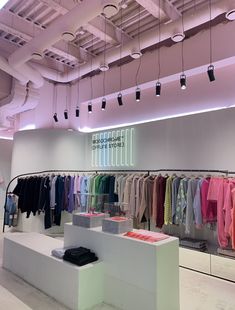 a clothing store with clothes on racks and hanging lights above the display area in front of it