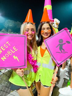 two girls in neon vests holding up signs