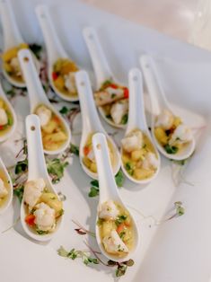 spoons filled with food sitting on top of a white tray next to each other