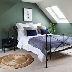 a bedroom with green walls, white bedding and a rug on the floor in front of it