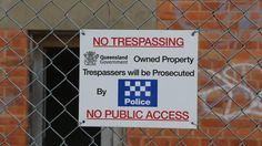 a no trespassing sign on a chain link fence in front of a brick building