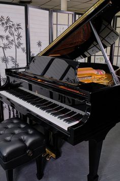 a black piano in a room with windows