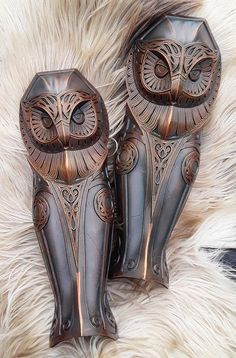 two metal owls sitting on top of a fur covered floor