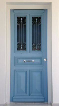 a blue front door with wrought iron grills on the top and side panels above it