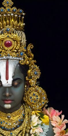 the statue is adorned with gold and blue jewels on it's head, surrounded by flowers