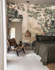 a bedroom with a bed, chair and wall papered in trees on the walls