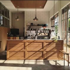 a person sitting at a counter in a room with lots of windows and wooden furniture