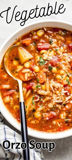 a bowl of vegetable orzo soup on a white tablecloth with a spoon in it