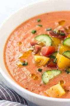 a white bowl filled with tomato soup and cucumber garnish on top