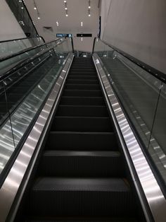 an escalator with glass railings leading up to the second floor