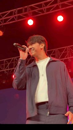 a man standing on top of a stage holding a microphone in his hand and singing