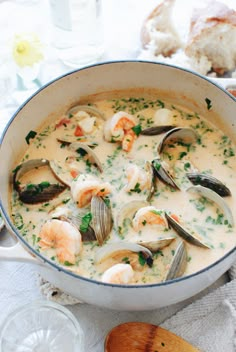 a large pot filled with seafood and clams on top of a table next to bread