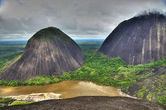 an aerial view of the mountains and river in the foreground with dark clouds overhead