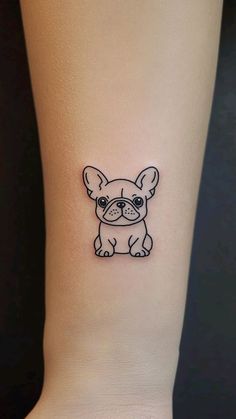 a small black and white dog tattoo on the ankle, with an outline of a french bulldog