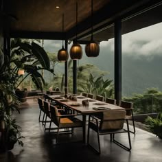 an outdoor dining area with table and chairs overlooking the mountain range in the distance, surrounded by greenery