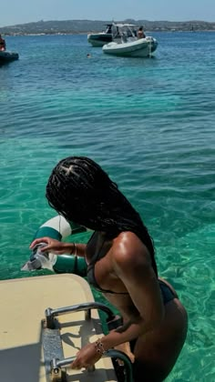 a woman sitting on the back of a boat in clear blue water