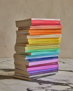 a stack of books sitting on top of a marble table next to a wall and floor