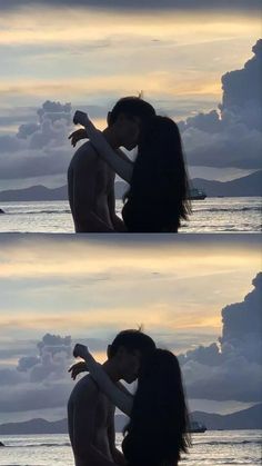 two people kissing in front of the ocean with clouds above them and one person holding his arm around the other's neck