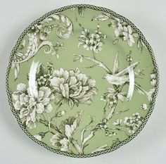 a green plate with flowers and birds on it