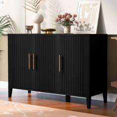 a black cabinet with two doors and some flowers on top in a living room area