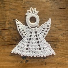 a crocheted angel ornament sitting on top of a wooden table