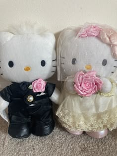 two hello kitty dolls sitting next to each other on the floor in front of a wall