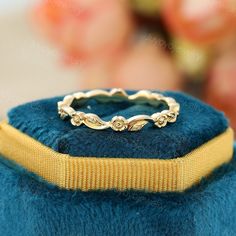 a gold ring sitting on top of a blue velvet box with flowers in the background