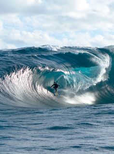 a man riding a wave on top of a surfboard in the ocean under a cloudy sky