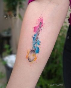 a woman's arm with a colorful watercolor tattoo on it and a brush