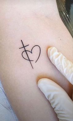 a heart with a cross tattoo on the side of someone's left arm and hand