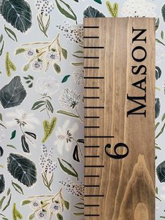 a wooden ruler sitting on top of a table next to a wallpaper covered with flowers