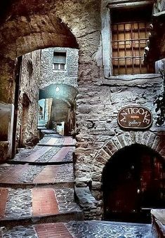 an alley way with stone walls and brick steps leading up to the entrance into a building