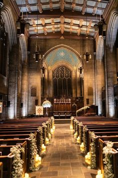 the inside of a church with rows of pews and lit candles on each side