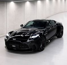 a black sports car is parked in a large room with white walls and flooring