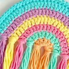 the crochet rainbow rug is made with yarn and has tassels on each side