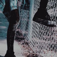 a person standing in front of a chain link fence with their feet on the ground