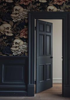 an open door leading to a room with skulls and flowers on the wall behind it