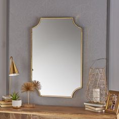 a mirror sitting on top of a wooden dresser next to a lamp and potted plant