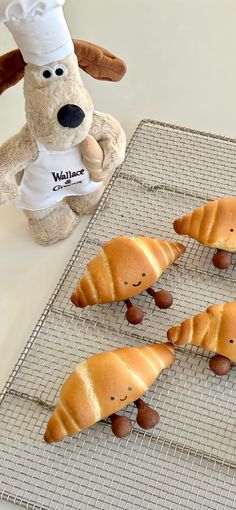 several croissants are on a cooling rack with a stuffed animal in the background