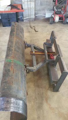 a large metal object sitting on top of a cement floor next to a pile of tools