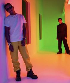 two young men standing in an empty room with neon lights on the walls and floor