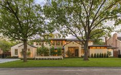 a large house with trees in front of it and grass on the side of the road