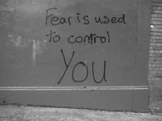 graffiti written on the side of a wall near a fire hydrant that reads fear is used to control you