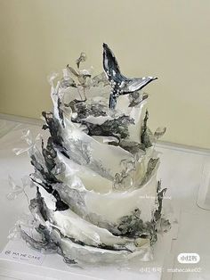 a three tiered cake is covered in frosting and has birds perched on it