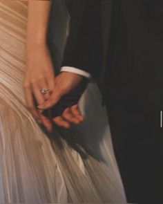 a man and woman holding hands while wearing wedding rings