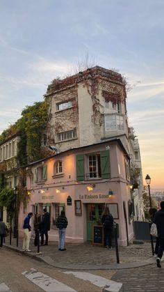 people are standing in front of a building with ivy growing on the roof and windows