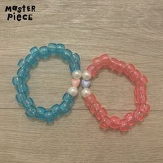 two beaded bracelets with seashell charms on them sitting on a wooden surface