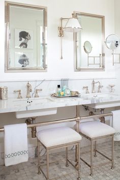 two sinks and mirrors in a bathroom with white marble counter tops, gold faucets and chrome fixtures