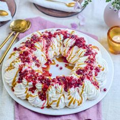 a white plate topped with a bundt cake covered in whipped cream and cranberry sauce